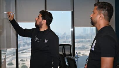 At the whiteboard, the Dubai skyline behind