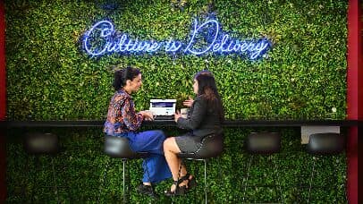 Two colleagues under the Culture is Delivery sign